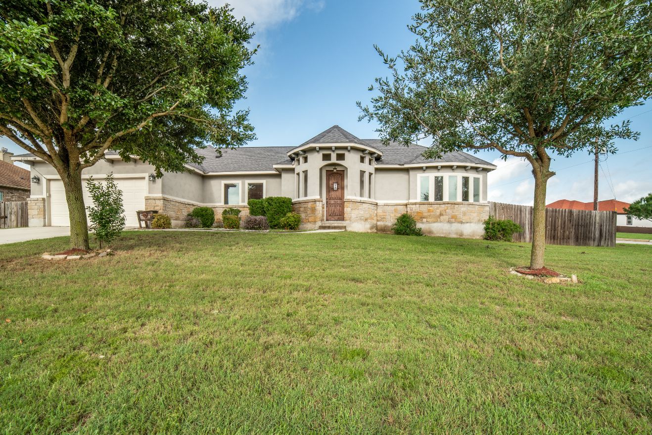 Stucco and stone home with a large front lawn